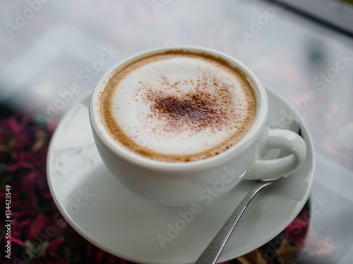 cappuccino coffee on white cut and on glass table with blur background
