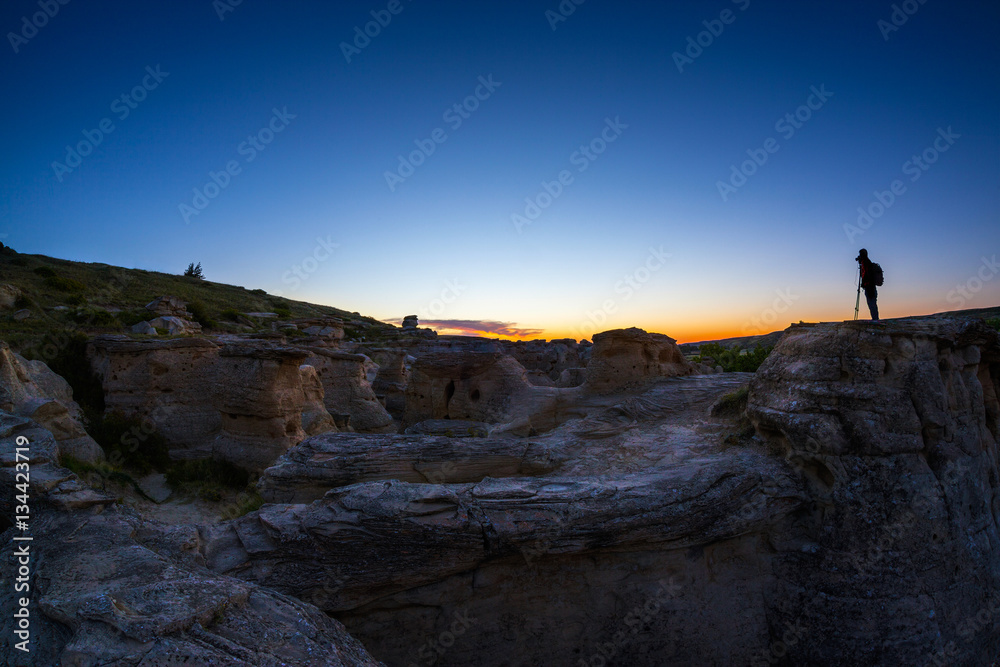 Photographer Catching the First Gleam of Sunrise at Writing on Stone Provincial Park in Alberta, Canada