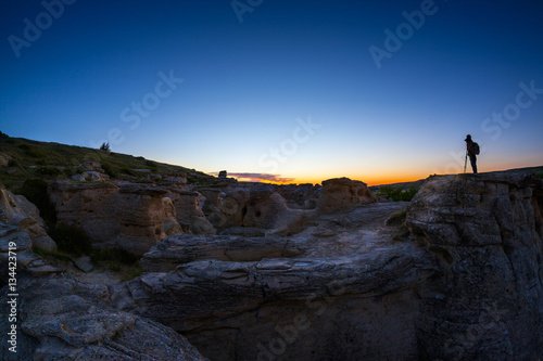 Photographer Catching the First Gleam of Sunrise at Writing on Stone Provincial Park in Alberta  Canada