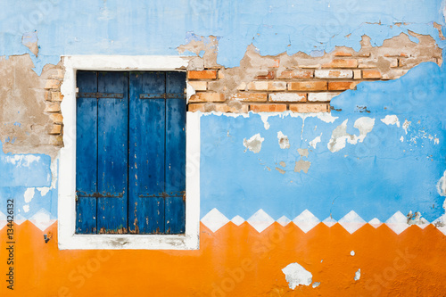 Canvas Print Ancient wall of the house and window with blue shutters.