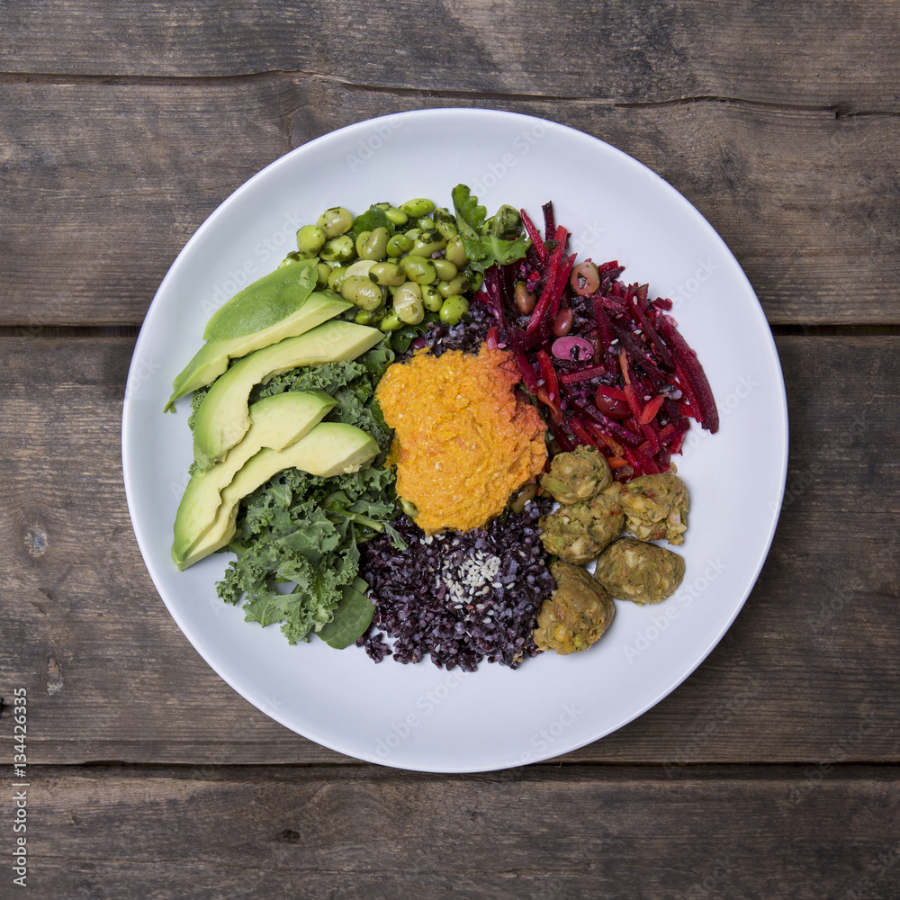 Nourish Bowl with Edamame, Black Rice, Avocado, Spinach, kale, carrot, cashews and beetroot on a Rustic wood background Nourish Bowl with Edamame, Black Rice, Avocado, Spinach, kale, carrot, cashews and beetroot on a Rustic wood background