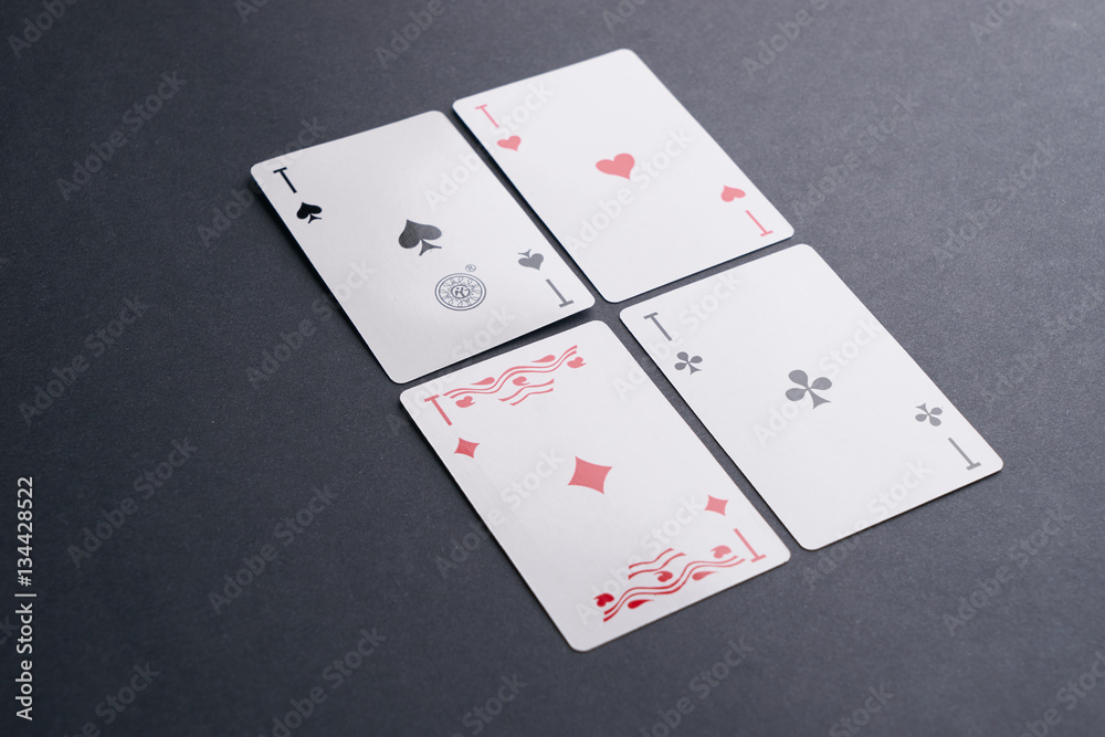 High Angle View of Four Playing Cards Spread Out on Dark Background Showing Aces from Each Suit - Hearts, Clubs, Spades and Diamonds High Angle View of Four Playing Cards Spread Out on Dark Background Showing Aces from Each Suit - Hearts, Clubs, Spades and Diamonds