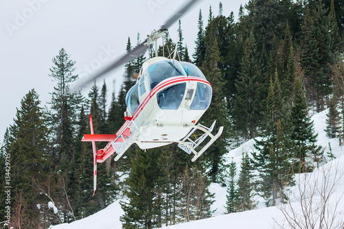 The helicopter landed in the mountains in winter, raising a clou