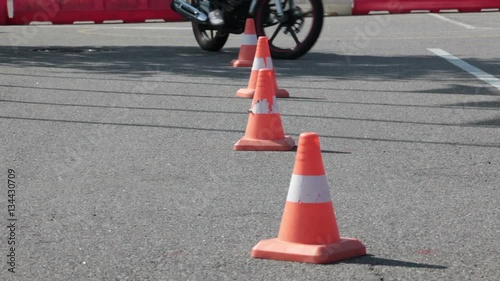 L- driver motorcyclist doing wave exercise with cones on the motorbike on the skill training asphalt motordrome. Russian driver school
 photo