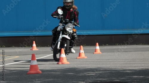 Motorcyclist makes wave-driving exercise with cones on the motorbike on the skill training asphalt motordrome. Russian driver school
