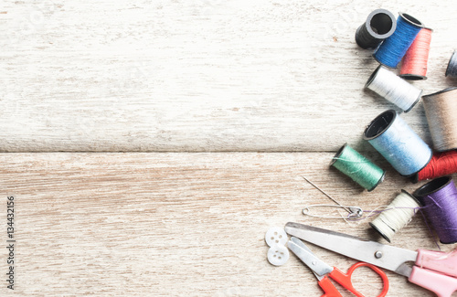 Sewing accessories,spools of thread with scissors on wood 