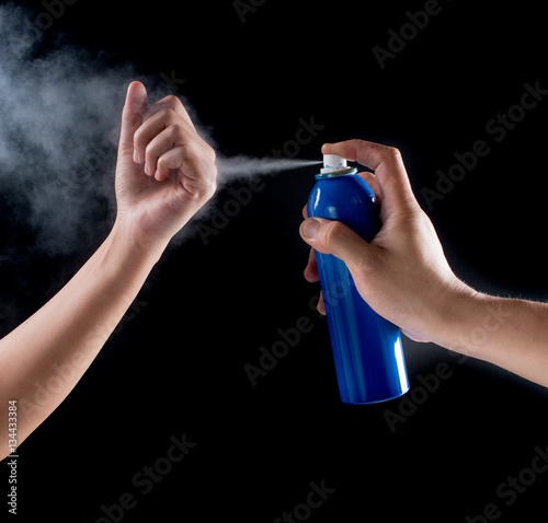 Analgesic spray can spraying on arm with black background,medica