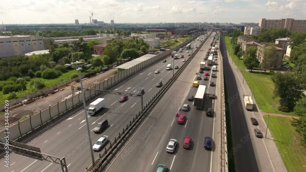 Vehicles drive at teh lanes of city highway, aerial view. Orbital freeway encircling city is in Rybatskoye municipality, Nevsky district Vehicles drive at teh lanes of city highway, aerial view. Orbital freeway encircling city is in Rybatskoye municipality, Nevsky district