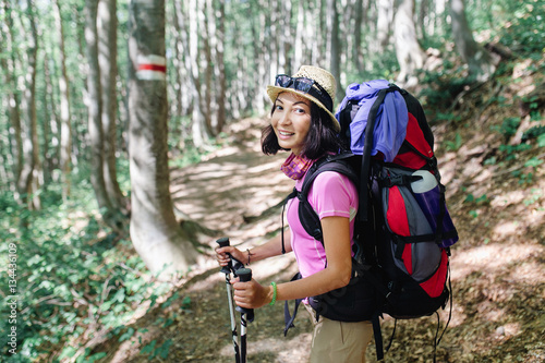 Hiker woman with backpack on marked forest trail in the woods