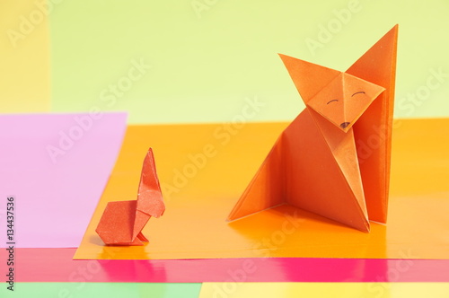 Paper origami rabbit and fox are isolated on a colorful background