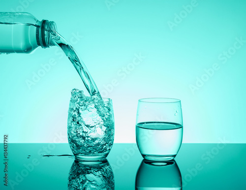 Bottle with creative splashing water in the glass