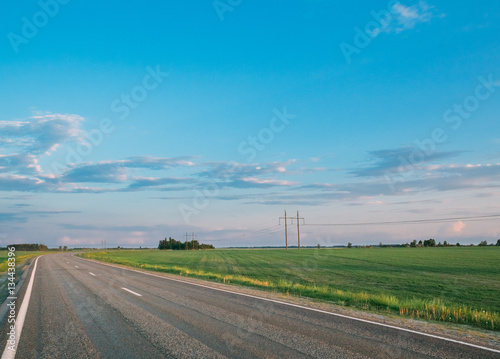 Green field and asphalt open road