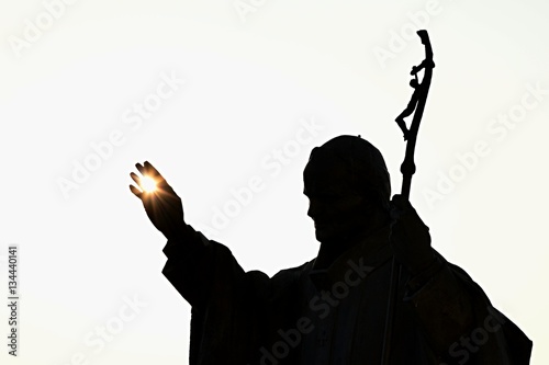 Canvas Print Silhouette of statue of pope John Paul The Second with afternoon sun in his palm