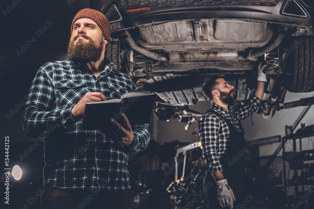 Bearded mechanics male inspecting car.