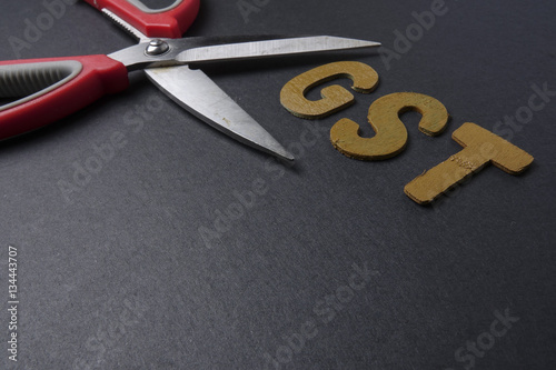 Scissors and word of GST on black background
