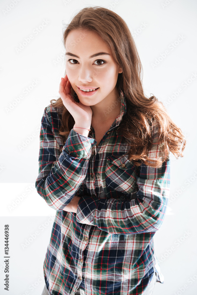 Smiling charming young woman in plaid shirt standing and posing Smiling charming young woman in plaid shirt standing and posing