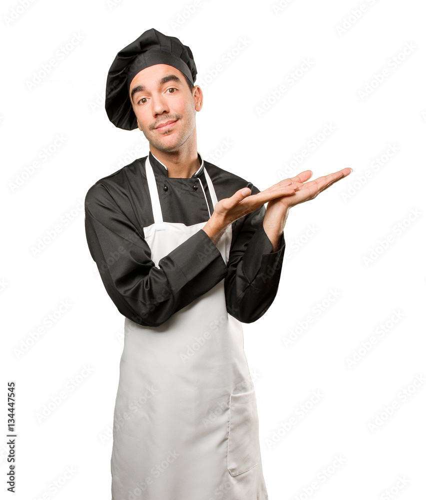 Satisfied young chef doing a show gesture Satisfied young chef doing a show gesture