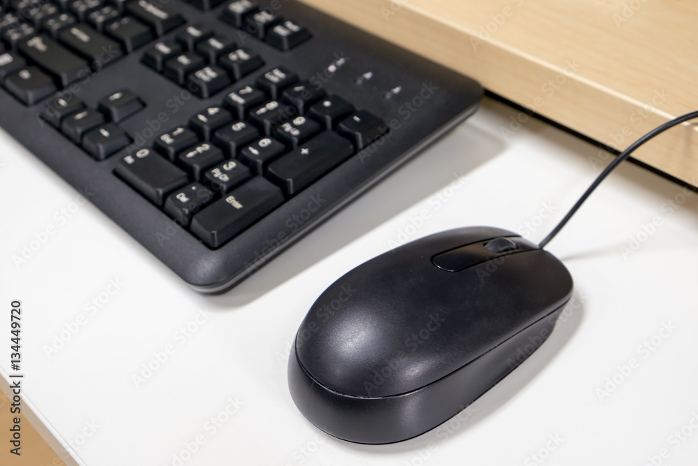 Closeup shot of black mouse and part of keyboard, selective focus on mouse, on working desk Closeup shot of black mouse and part of keyboard, selective focus on mouse, on working desk