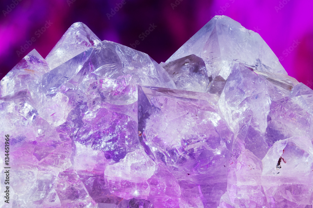 Fototapeta premium Beautiful natural amethyst crystals against purple background.