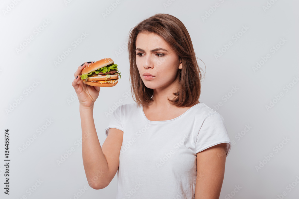 Confused hungry woman eating fastfood