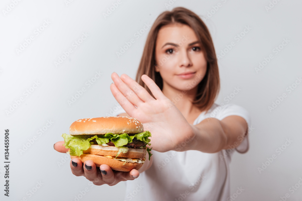 Serious young woman showing fastfood to camera Serious young woman showing fastfood to camera