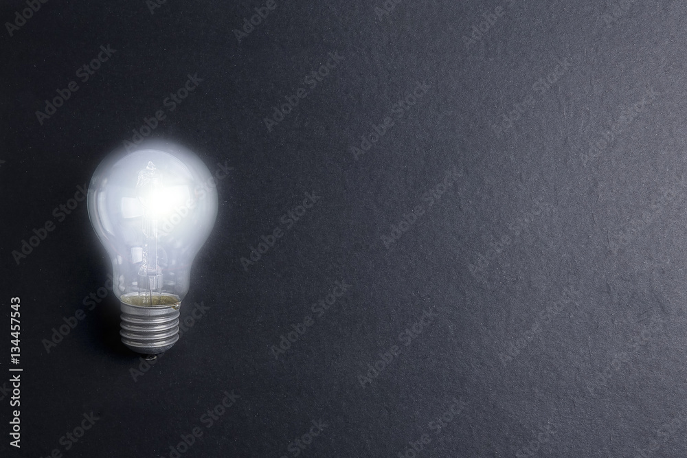Idea concept word IDEA. Light of bulb on grey background. Low light Idea concept word IDEA. Light of bulb on grey background. Low light