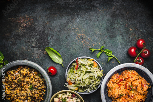 Foto Delicious various vegetarian salads in bowls on dark rustic background, top view, border