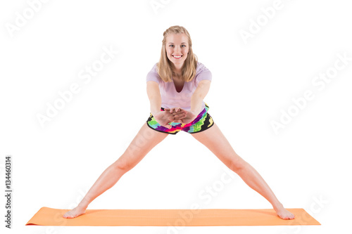 Smiling woman in sportswear stretching back and legs on a mat
