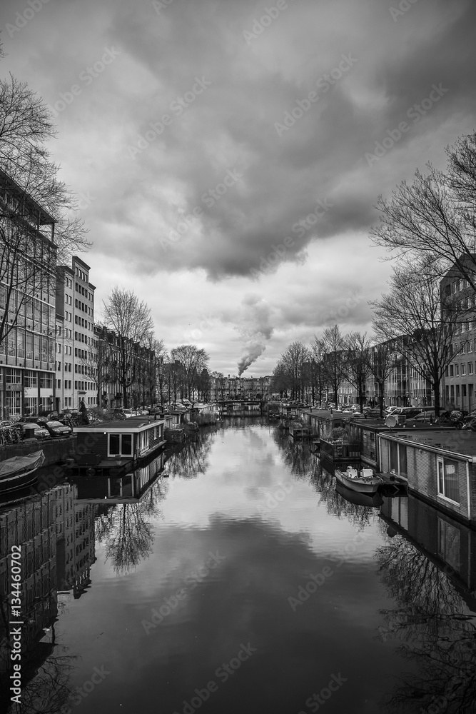 Canal in Amsterdam with dramatic stormy clouds, in the background it seems the factory chimney is producing the clouds