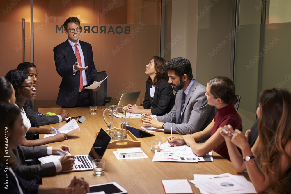 Businessman stands gesturing to colleagues at a meeting Businessman stands gesturing to colleagues at a meeting