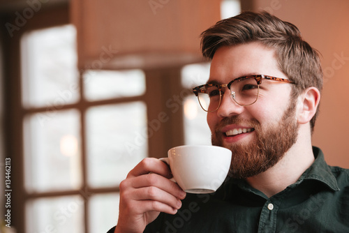 Happy bearded young man drinking coffee.