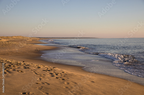 view on a beach at sunset with golden sand and quiet sea