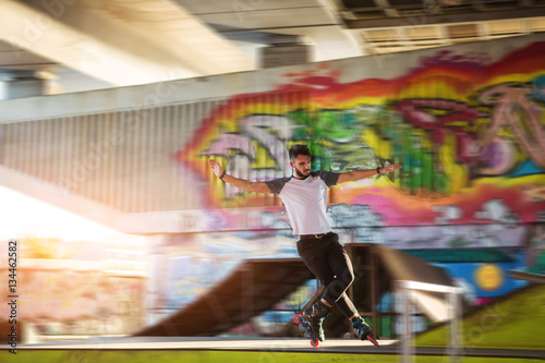 Young man is rollerblading. Rollerblader and graffiti. High speed and perfect balance.