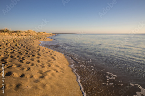 view on a beach at sunset with golden sand an quiet sea