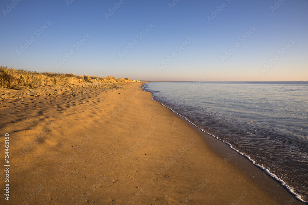 view on a beach at sunset with golden sand an quiet sea view on a beach at sunset with golden sand an quiet sea