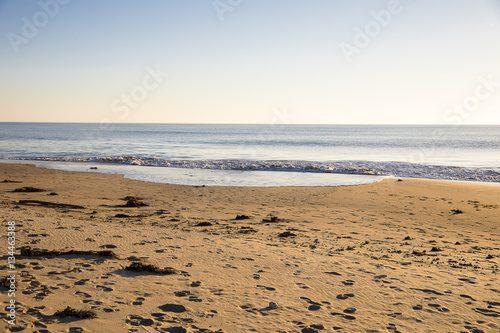 view on a beach at sunset with golden sand and quiet sea
