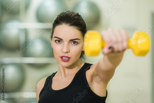 beautiful girl doing exercise with yellow dumbbell