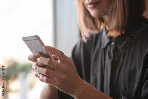 Cropped image of young woman using mobile phone.