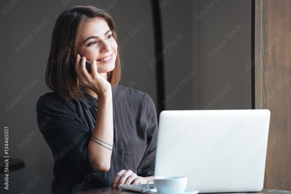Attractive woman sitting at the table talking by phone Attractive woman sitting at the table talking by phone