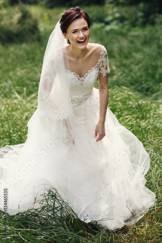 Gorgeous princess bride in white dress posing in sunny park