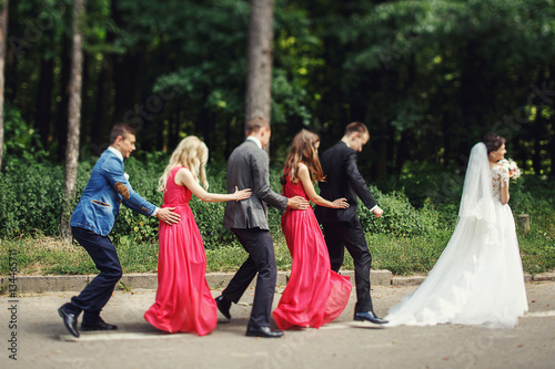 Newlyweds with groomsmen & bridesmaids having fun outdoors © syrotkin
