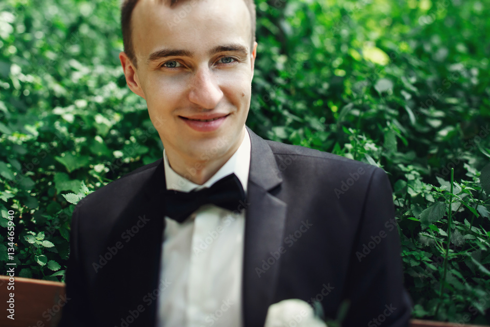 Handsome groom in elegant suit posing on bench face closeup Handsome groom in elegant suit posing on bench face closeup
