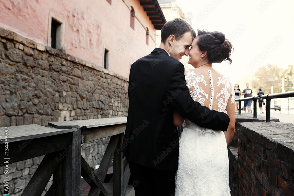 Groom embraces bride tender while they kiss on the bridge Groom embraces bride tender while they kiss on the bridge