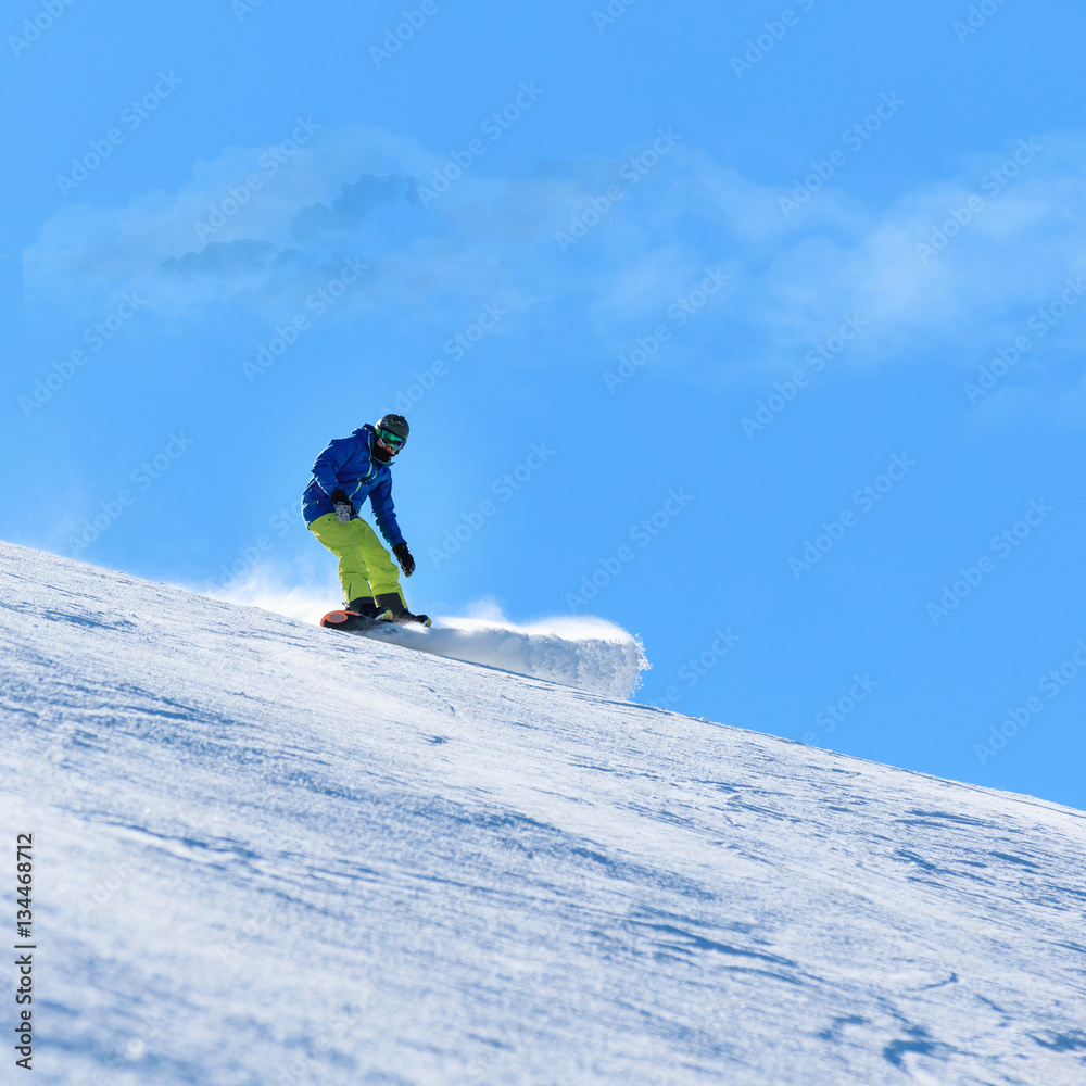 Male snowboarder on the slope sliding down the hill