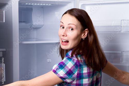 woman standing near open empty fridge