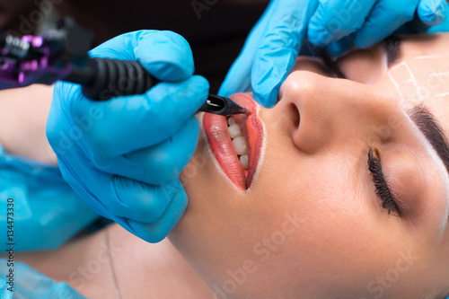 Cosmetologist making permanent makeup on woman's face