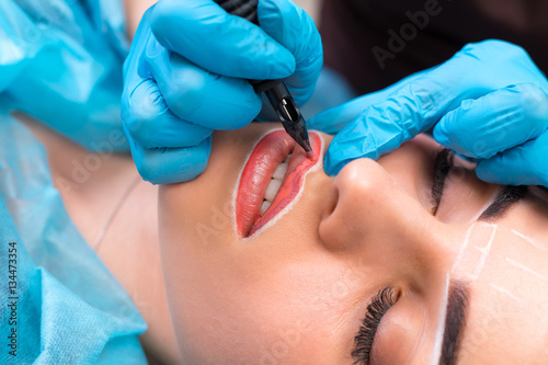 Cosmetologist making permanent makeup on woman's face