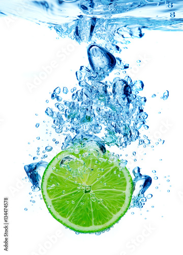 Lime dropped in a water on white background