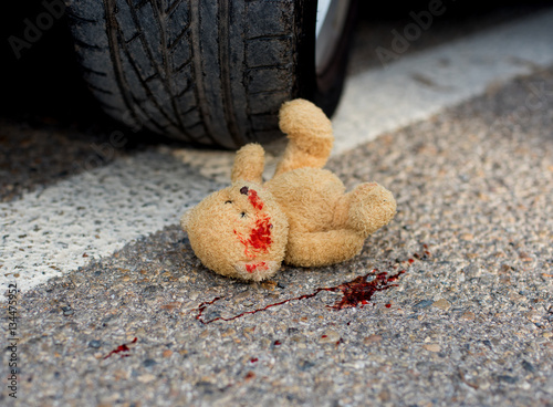 Fotografie toy bear in the blood under the car wheels