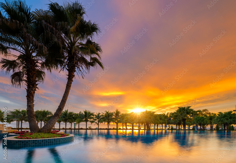 Obraz premium Beautiful sunset over the sea with a view at palms on the white beach